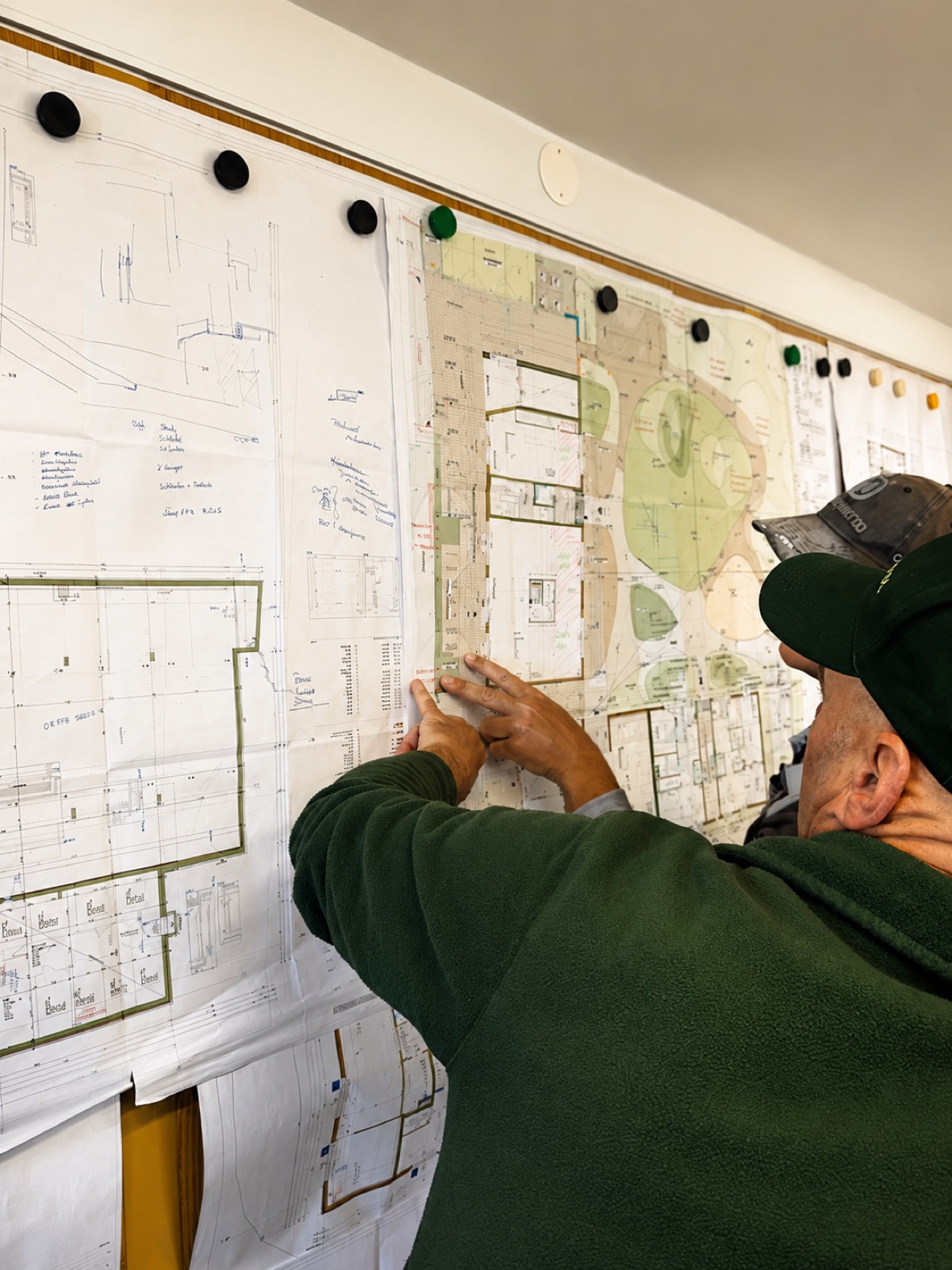 Max plant eine Außenanlage anhand von Bauplänen an der Planwand