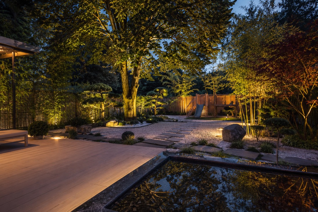 Japanischer Garten mit Ahorn, Kiesfläche, Wasserbecken und Holzdeck bei Abendbeleuchtung