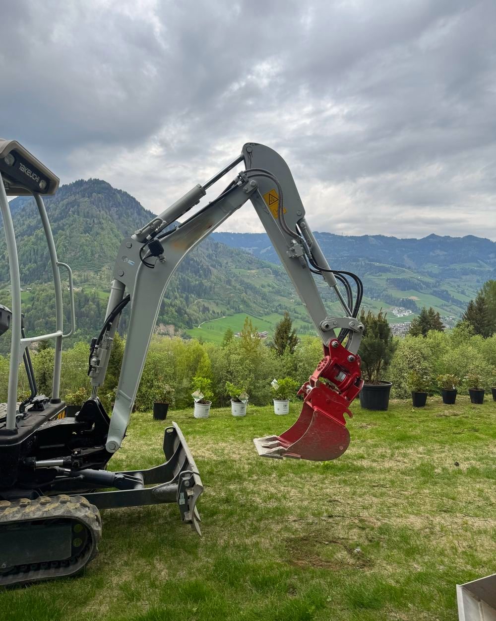 Minibagger von DerPflanzenProfi auf einer Gartenbaustelle vor Bergkulisse